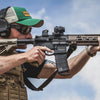 Person holding a rifle with a clear sky background