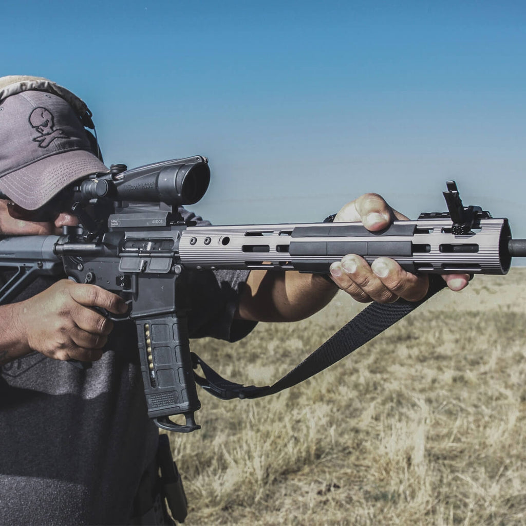 Person holding a rifle with a scope in an outdoor setting