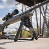 Rifle with scope and bipod on a wooden platform with a blurred background