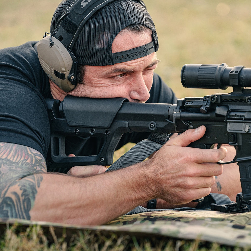 Man aiming a rifle with a scope in a natural setting