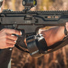 Close-up of a person holding a rifle with a scope, outdoors.