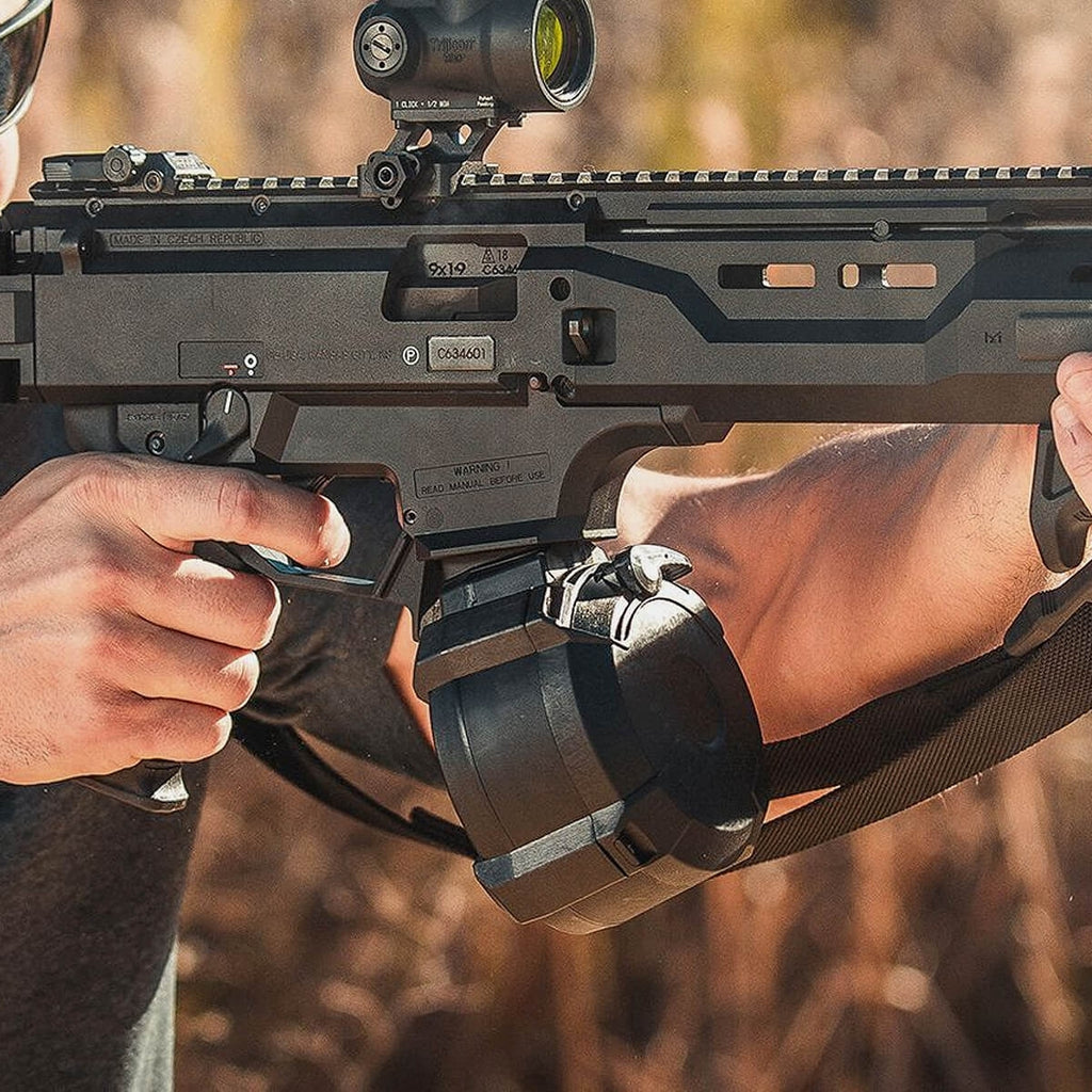 Close-up of a person holding a rifle with a scope, outdoors.