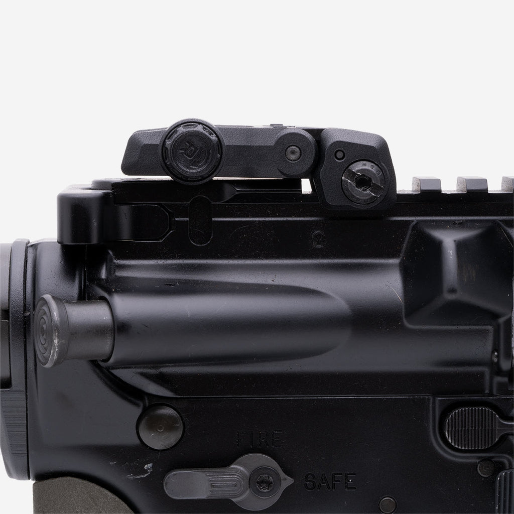 Close-up of a black firearm with a sight on a white background