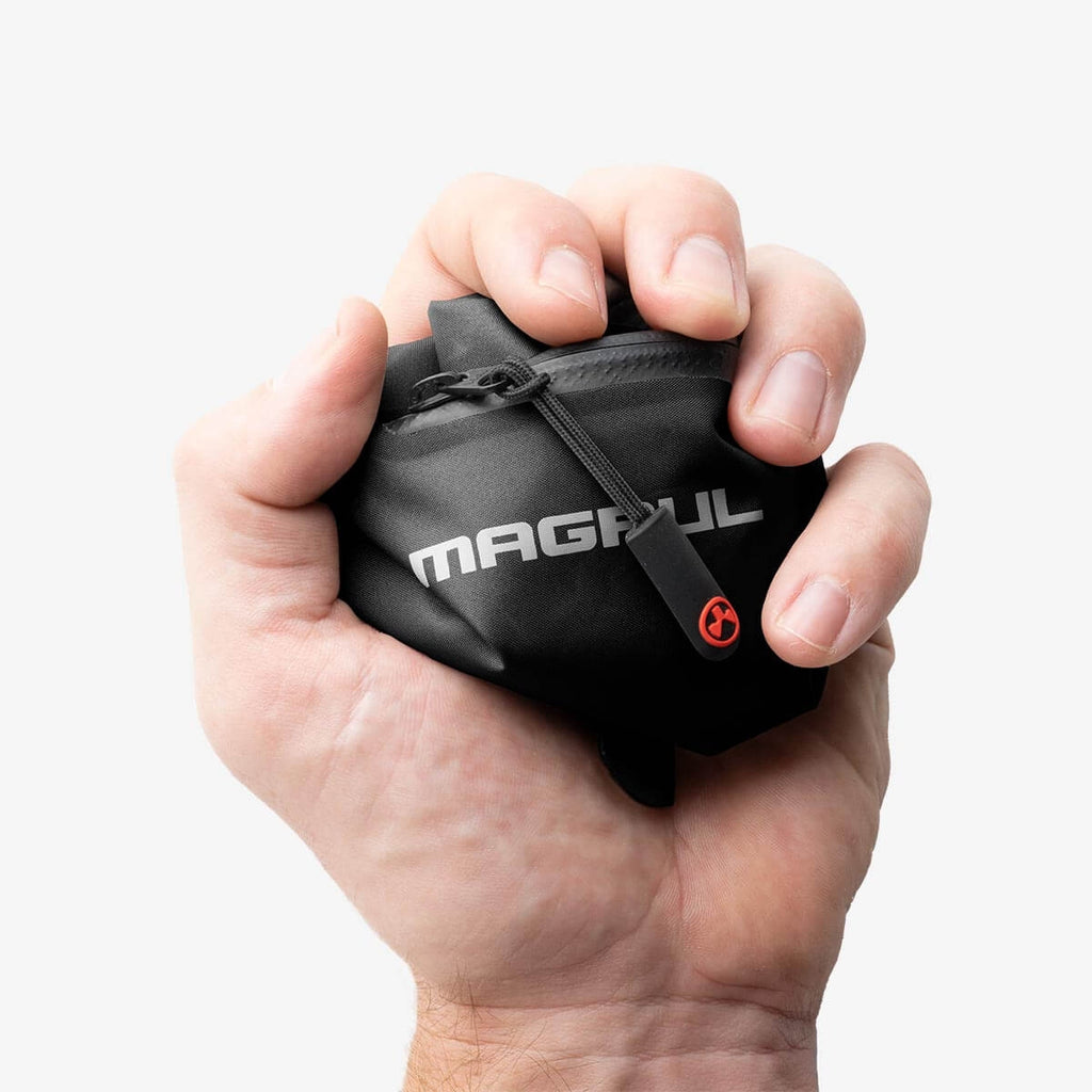 Hand holding a black Magpul bag against a white background