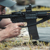 Person holding a rifle with a scope in a natural setting