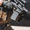 Person holding a rifle with tactical gear and gloves in a close-up shot.