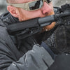 Person in winter gear with a rifle in a snowy environment