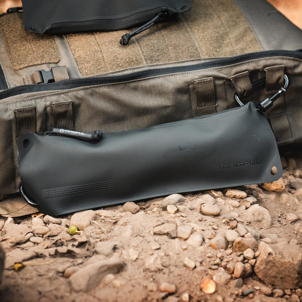Black waterproof bag with 'Pacsafe' branding on a rocky ground