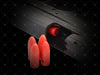 Red silicone bullet-shaped objects in front of a gun on a dark background